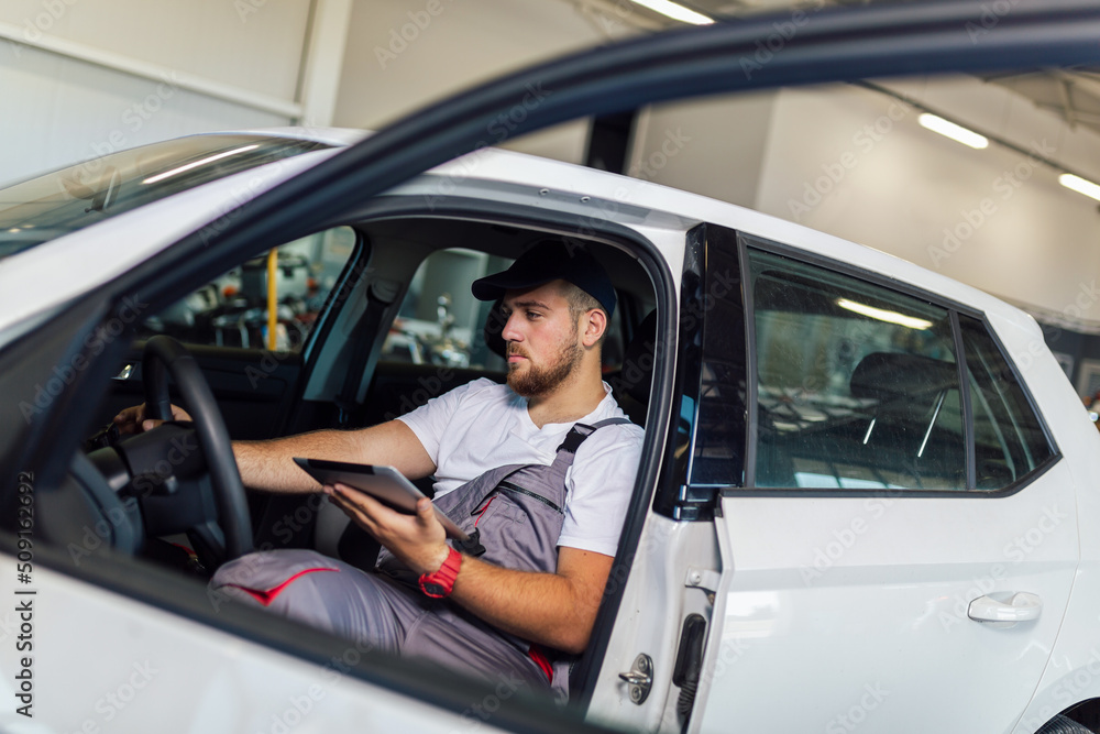 Professional car mechanic working in auto repair service using digital tablet Professional car mechanic working in auto repair service using digital tablet