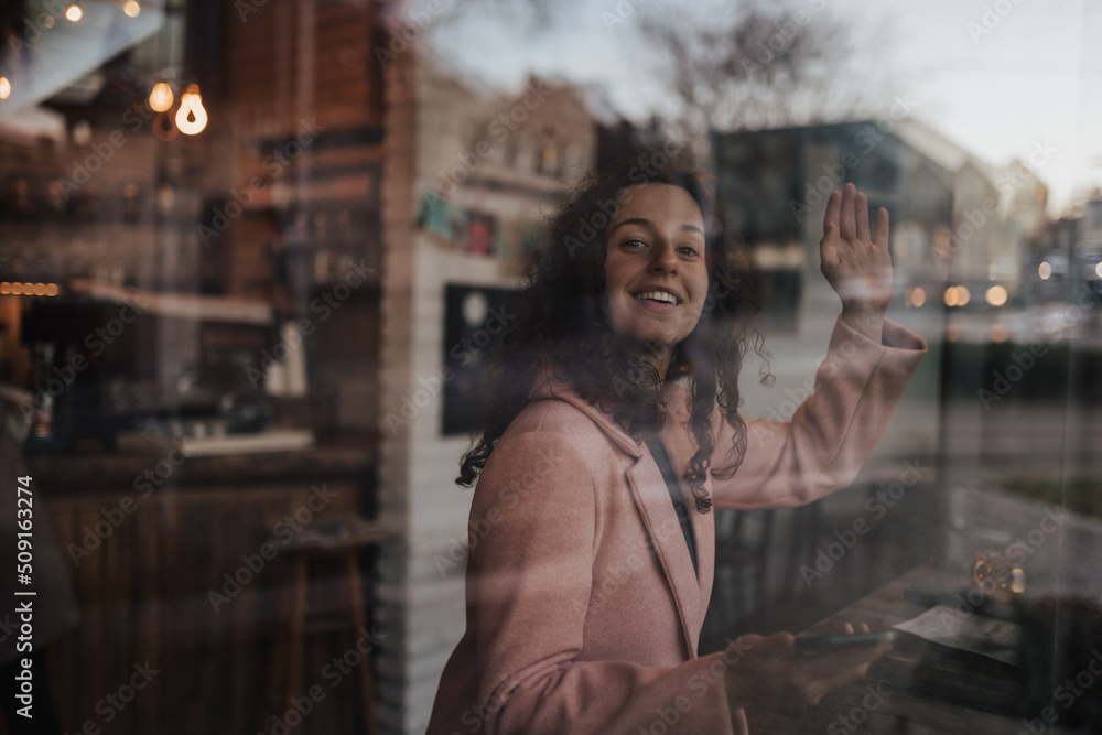 Young woman drinking tea and looking out of the cafe window while enjoying her leisure time alone