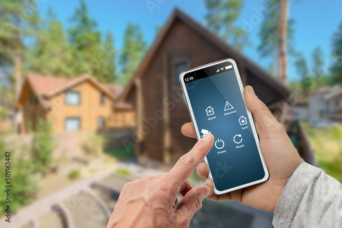 Male hands with smart home menu icons on digital smartphone screen over country cottage background