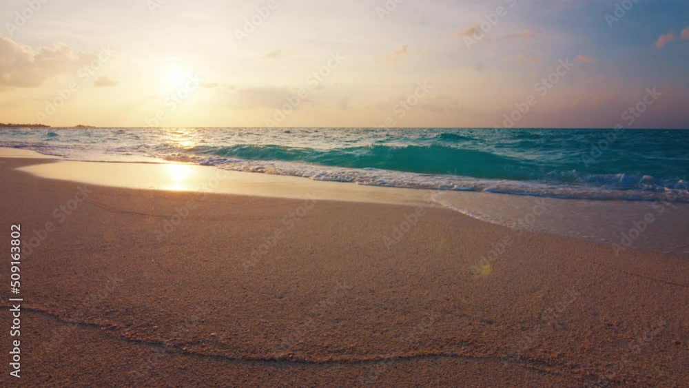 Tropical sea at sunset. Maldivian beach with gentle rolling waves on the tropical island of Thulusdhoo in Maldives Tropical sea at sunset. Maldivian beach with gentle rolling waves on the tropical island of Thulusdhoo in Maldives