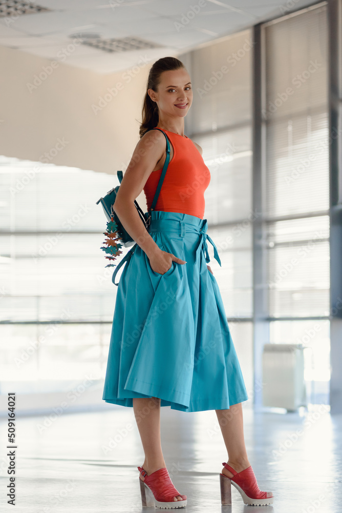 Stylish happy brunette with backpack waiting for trainer in gym