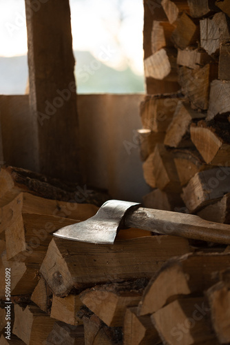 The ax lies on the wood in the shed. Close-up