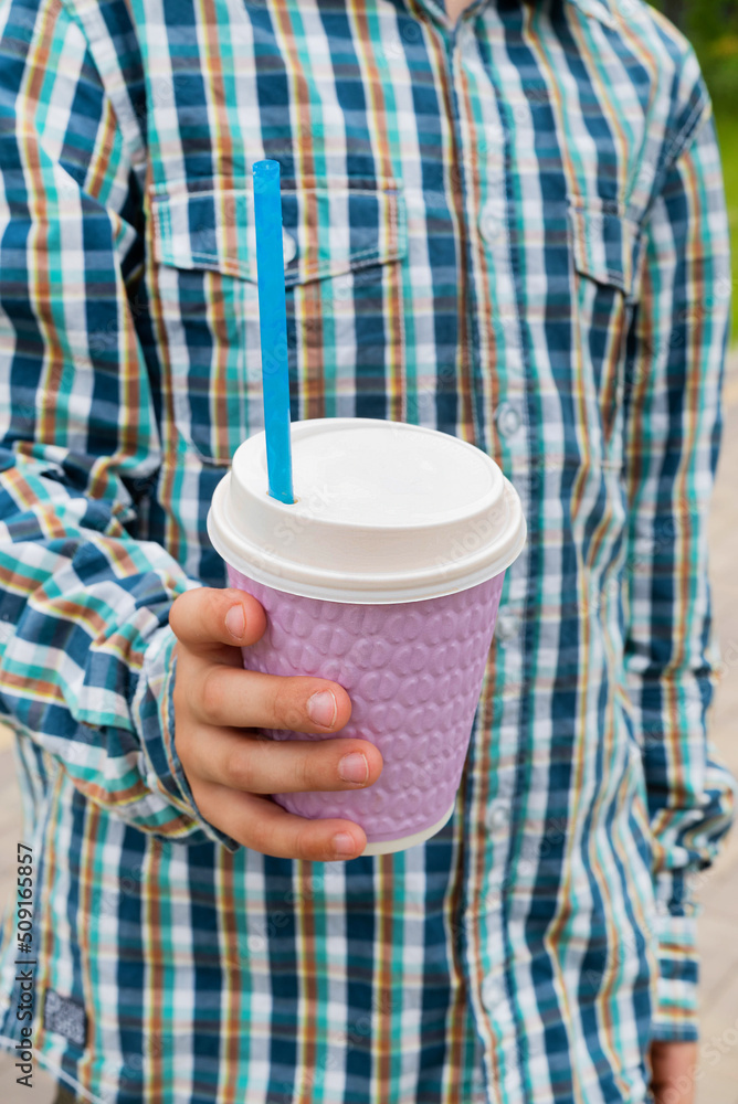 Blurred image of a cup with a coffee drink in the hands of a boy. Blurred image of a cup with a coffee drink in the hands of a boy.