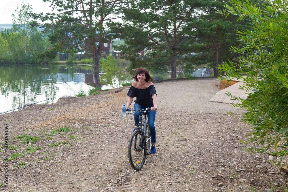 Obraz premium Woman 40-44 years old on a bicycle. The girl decided to get in shape beginning of summer.