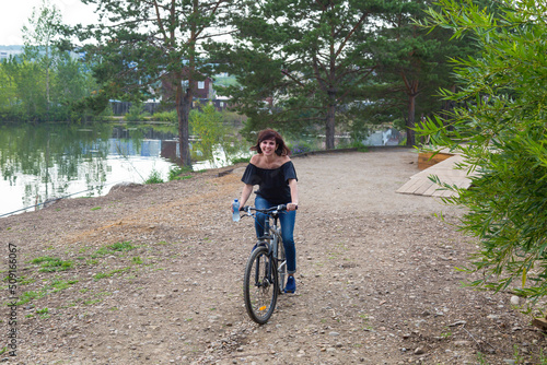 Woman 40-44 years old on a bicycle. The girl decided to get in shape beginning of summer.