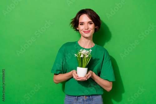 Photo of sweet funny woman wear casual t-shirt holding small plant pot isolated green color background