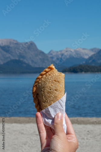 fried trout empanada, typical Argentine food, with a landscape of lake and mountains