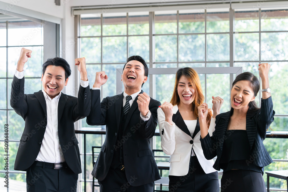 A group of young businessmen in suits, Asians, are determined and excited about their work. and encourage the team members by raising their hands happily A group of young businessmen in suits, Asians, are determined and excited about their work. and encourage the team members by raising their hands happily