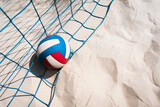 Blue color volleyball net, blue red white beach volleyball ball and yellow sands on a beach.