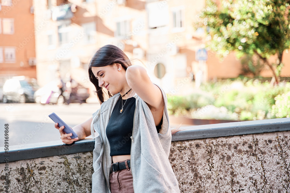 Fototapeta premium Happy woman using a smart phone in the street with an unfocused background