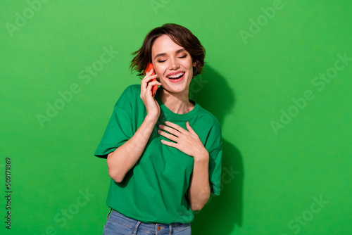 Photo of dreamy funky woman wear casual t-shirt communicating modern gadget isolated green color background
