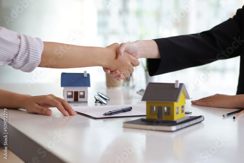 Businesswoman or real estate agent shakes hands with a client and asks them to legally sign a contract of agreement.