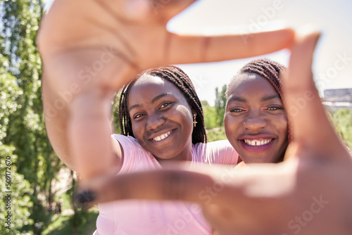 two African-American friends making a frame with their hands