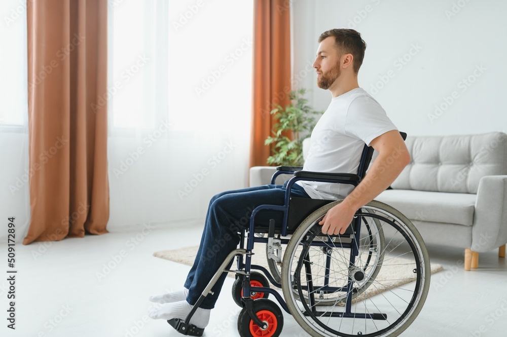 thoughtful young disabled man on wheelchair at home. thoughtful young disabled man on wheelchair at home.