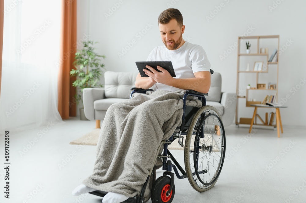 Modern young disabled man in wheelchair having video call. Modern young disabled man in wheelchair having video call.