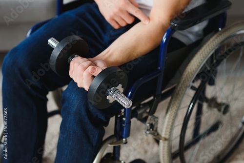 Man Disabled. Sports for Disabled. Male in Wheelchair with Dumbbells in Hands. Man with Dumbbells in Hands. Father Disabled Do Spotting. Sport at Apartment. Health Concept. Healthy Lifestyle