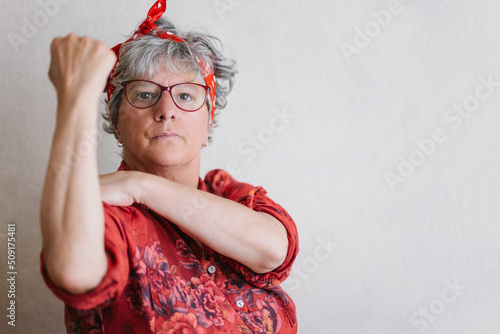 Serious elderly feminist showing muscles and looking at camera