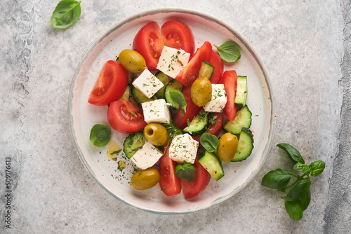 Greek salad. Fresh Greek salad with fresh vegetables, tomato, cucumber, green olives and feta cheese on old grey concrete table background. Top view.