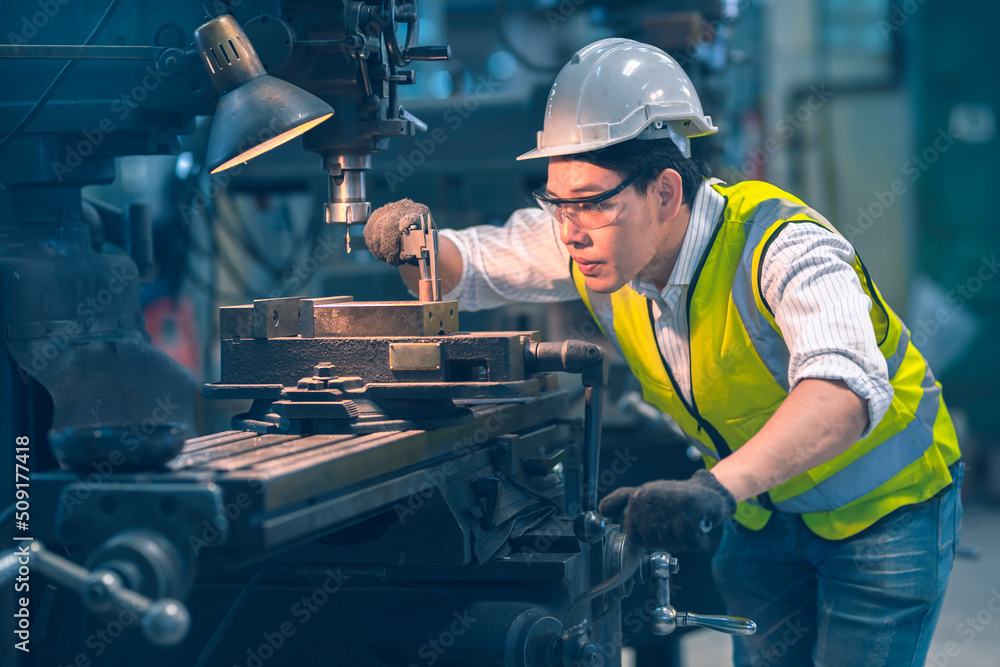 The white safety helmet engineer use a vernier caliper for a lathe for shaping the steel for a part follow blueprint machinery in the factory industrial The white safety helmet engineer use a vernier caliper for a lathe for shaping the steel for a part follow blueprint machinery in the factory industrial