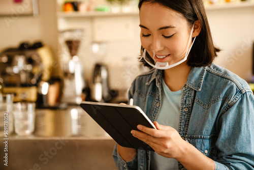 Young asian waitress woman working with tablet computer in cafe