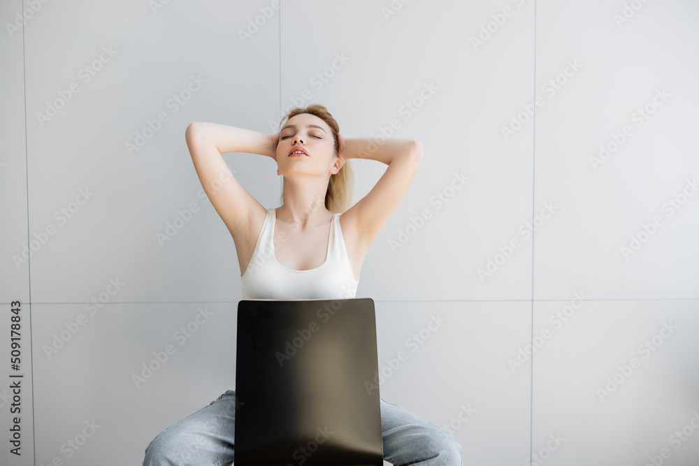 Pretty woman with closed eyes touching hair while sitting on chair at home. Pretty woman with closed eyes touching hair while sitting on chair at home.