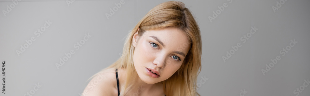 Portrait of blonde woman looking at camera isolated on grey, banner. Portrait of blonde woman looking at camera isolated on grey, banner.