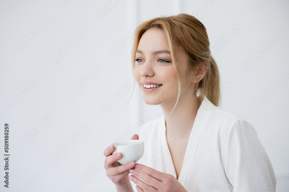 Pretty young woman holding cup and looking away at home. Pretty young woman holding cup and looking away at home.