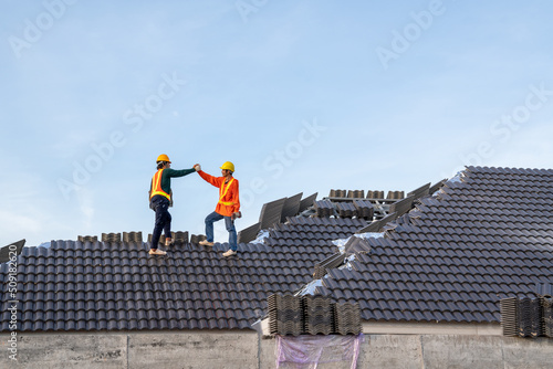 Teamwork of A Construction worker install new roof, Electric drill used on new roofs with Concrete Roof Tiles, Roofing tools.