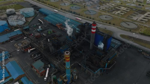 Fly around industrial factory emitting steam or smoke. Vehicles driving on road around. Port Elisabeth, South Africa
