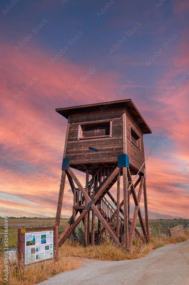 A wooden watchtower lookout tower on a field and a swamp created by the Axios river delta