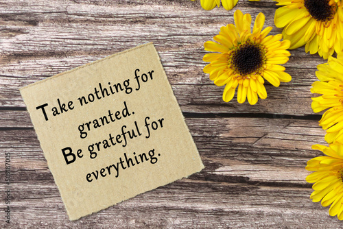 Foto Motivational quote on torn brown paper on wooden surface with sunflowers