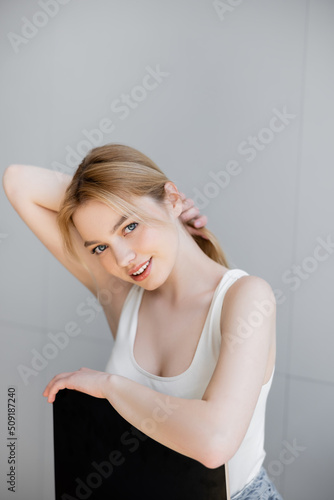 Young woman touching hair while sitting on chair at home.