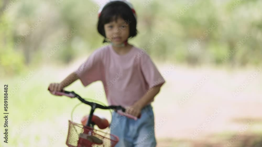 Thai Asian kid girl, aged 4 to 6 years old, looks cute, wears a helmet. and a bicycle She is play riding a bicycle to exercise in the park. It is a fun outdoor activity and learning about nature. Thai Asian kid girl, aged 4 to 6 years old, looks cute, wears a helmet. and a bicycle She is play riding a bicycle to exercise in the park. It is a fun outdoor activity and learning about nature.