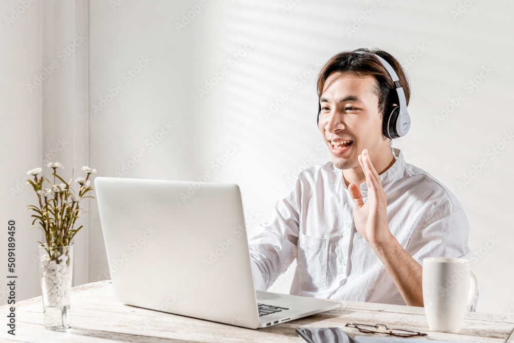 A concentrated Asian young businessman working at home office pleased happy cheerful on online meeting video or learning using laptop computer for job work or make good dealing. Work and win concept A concentrated Asian young businessman working at home office pleased happy cheerful on online meeting video or learning using laptop computer for job work or make good dealing. Work and win concept