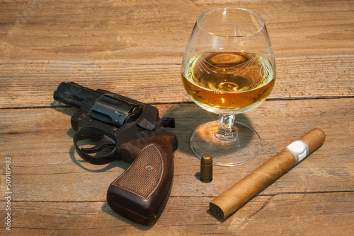 Symbols of Mafia Power. Revolver, cognac, cigar and a projectile, personal paraphernalia of a mafia boss.