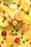 Tropical fruits and berries on a yellow background, flat lay.