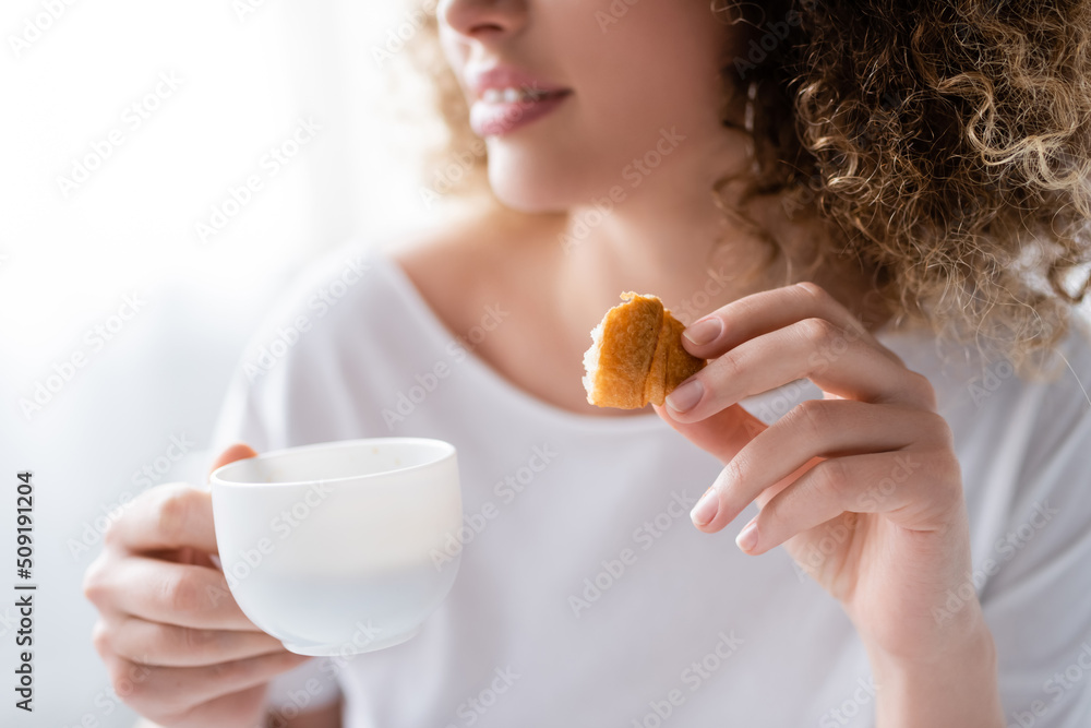 partial view of blurred woman with coffee cup and piece of delicious croissant. partial view of blurred woman with coffee cup and piece of delicious croissant.