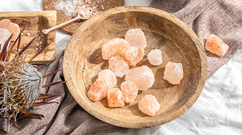Spa composition with pieces of sea salt in a wooden plate.