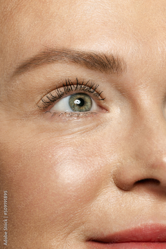 Fototapeta premium Close-up portrait of young woman's eyes with wrinkles. Female model with well-kept skin. Concept of women's health and beauty, cosmetology, cosmetics. Anti-aging.
