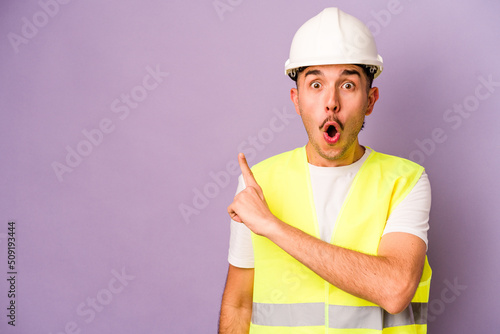 Young hispanic worker man isolated on purple background pointing to the side photo