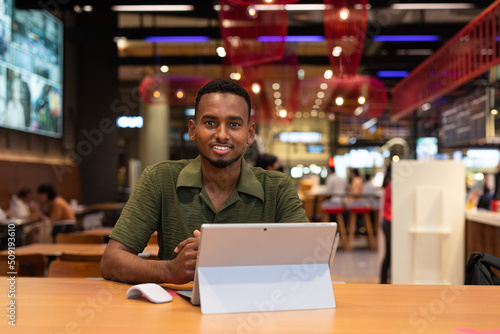 Portrait of handsome young black man using laptop computer in coffee shop