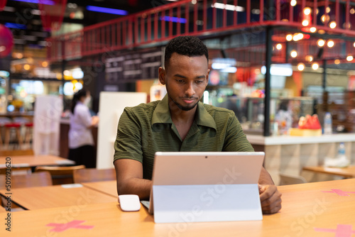 Portrait of handsome young black man using laptop computer in coffee shop