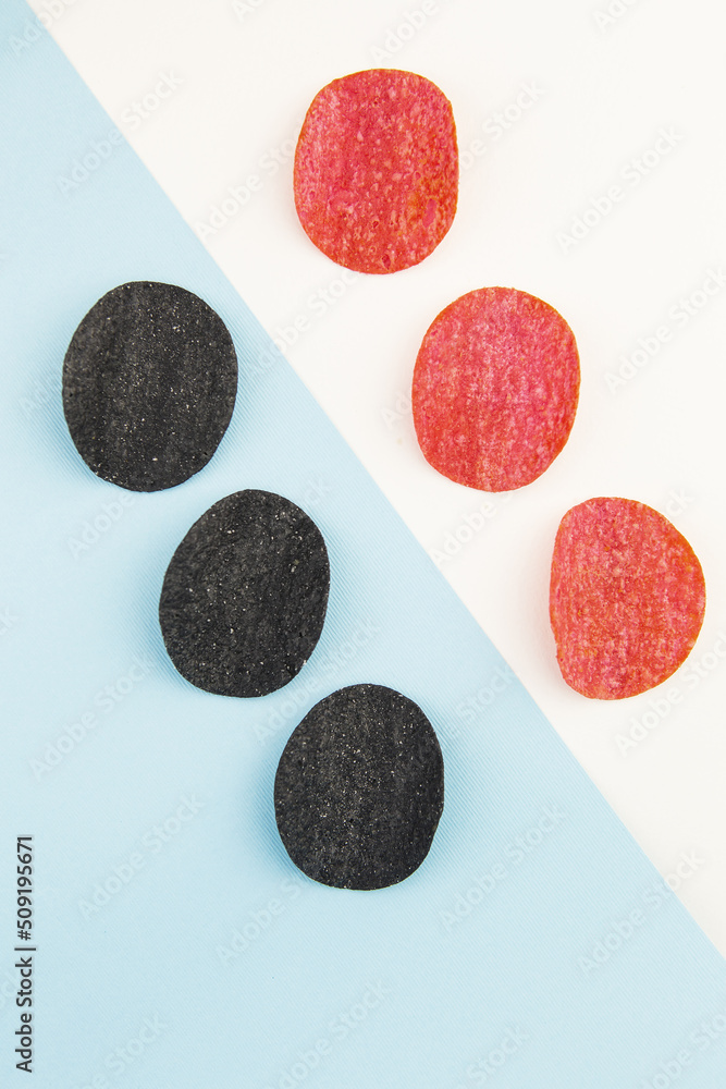 Red and black potato chips with salt, chili pepper. Isometric drawing. Chips background on white and blue background. Red and black potato chips with salt, chili pepper. Isometric drawing. Chips background on white and blue background.