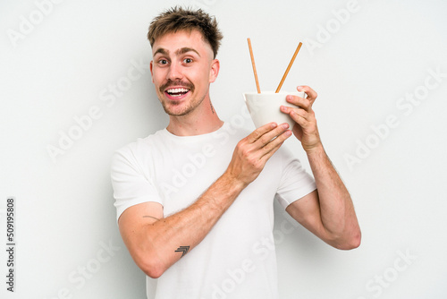Young caucasian man eating noodles isolated on white background