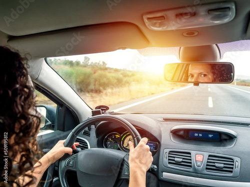 Pretty brown-haired woman driving a car and looking in the mirror