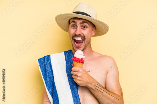 Young caucasian man holding an ice cream isolated on yellow background