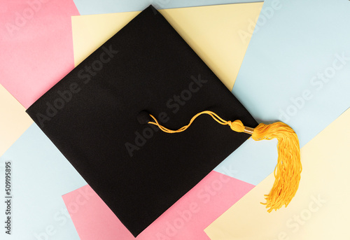 Bild auf Leinwand Black graduation cap or hat with yellow tassel on colorful pastel background edu
