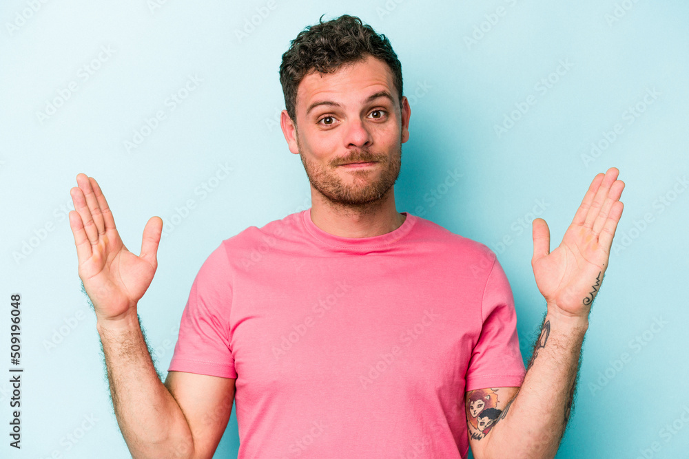 Fototapeta premium Young caucasian man isolated on blue background holding something little with forefingers, smiling and confident.