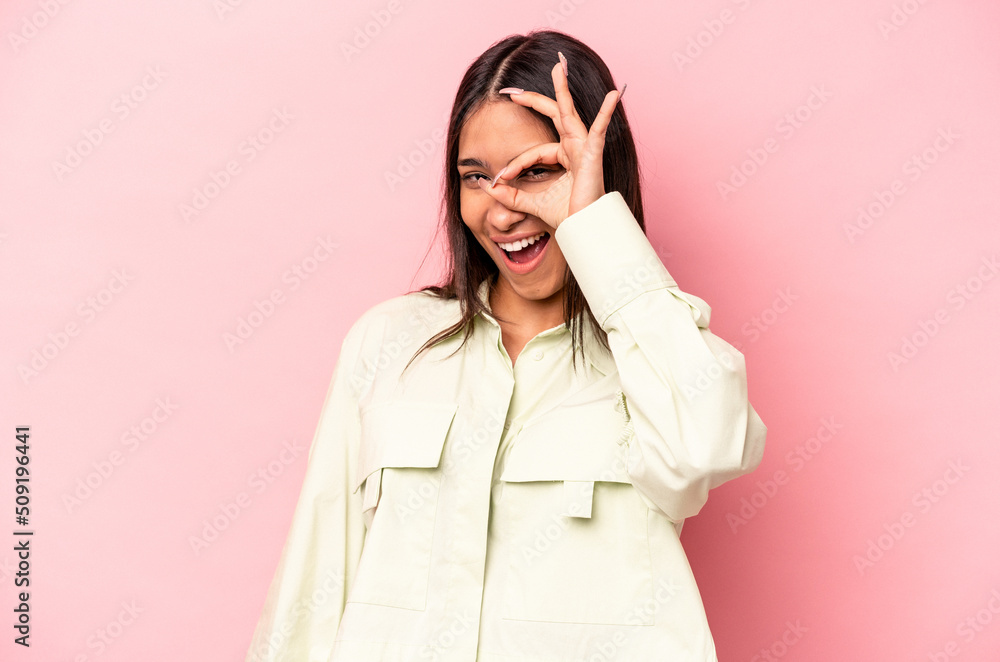 Young hispanic woman isolated on pink background excited keeping ok gesture on eye. Young hispanic woman isolated on pink background excited keeping ok gesture on eye.