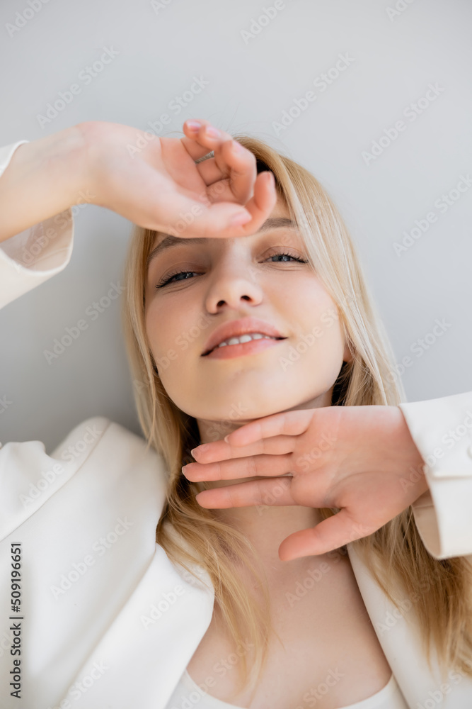 Portrait of smiling blonde woman in jacket looking at camera isolated on grey. Portrait of smiling blonde woman in jacket looking at camera isolated on grey.